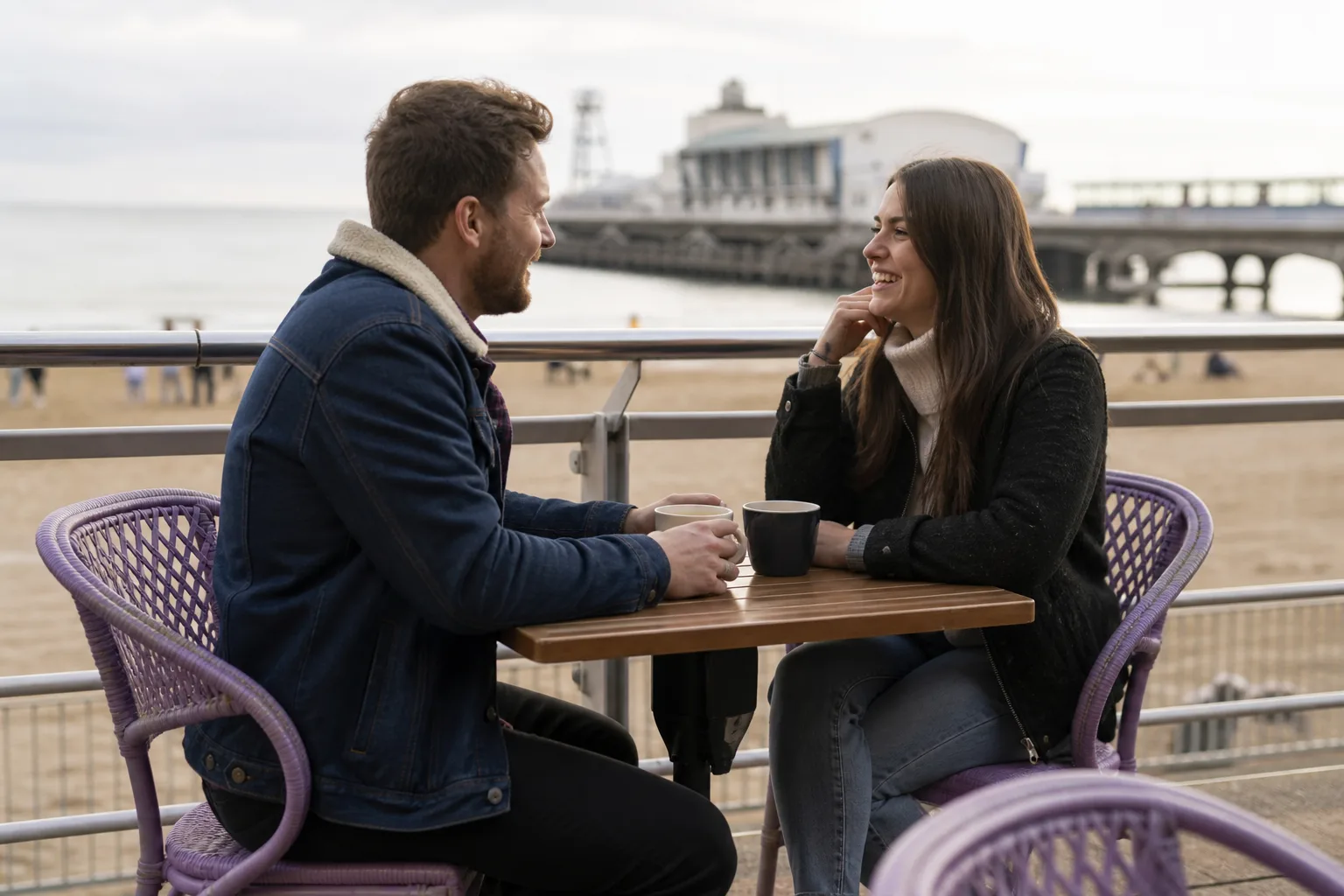 Two people walking together beside Bournemouth beach and pier